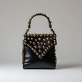 black leather handbag with gold-toned stud and chain detailing.